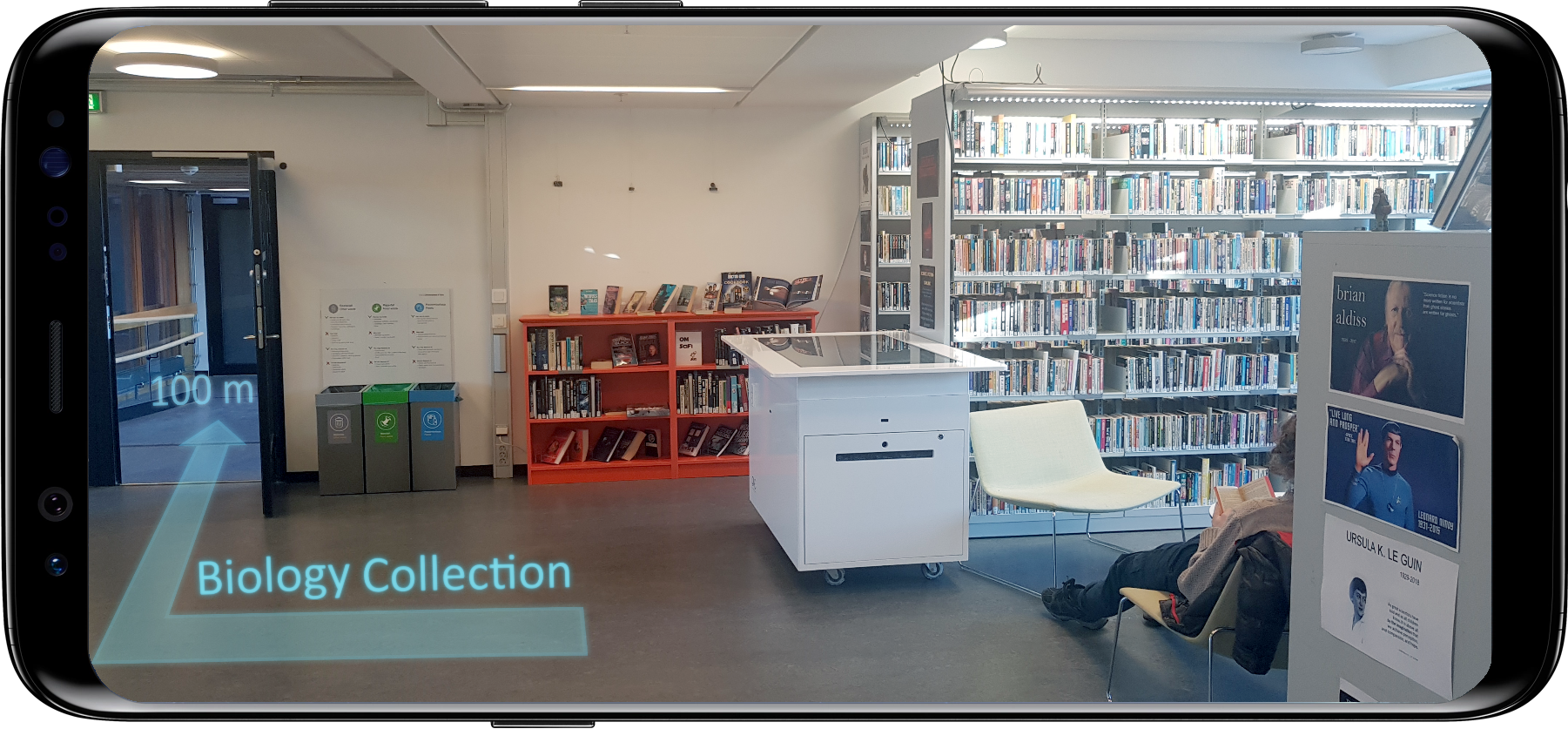 Mobile phone screen with AR directions and arrow superimposed on camera view of library scne, with moveable object and person visible.